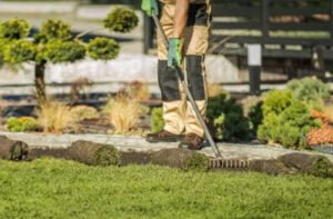 Une photo d’un jardinier en train de ratisser la pelouse dans un jardin